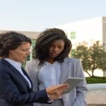 Duas mulheres com tablet nas mãos realizando a administração de um condomínio