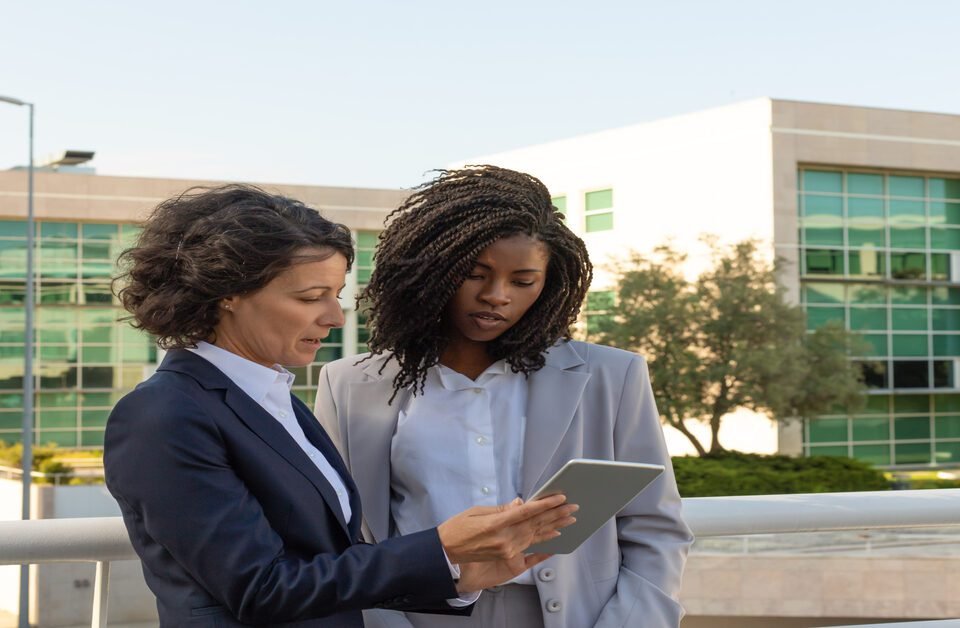 Duas mulheres com tablet nas mãos realizando a administração de um condomínio
