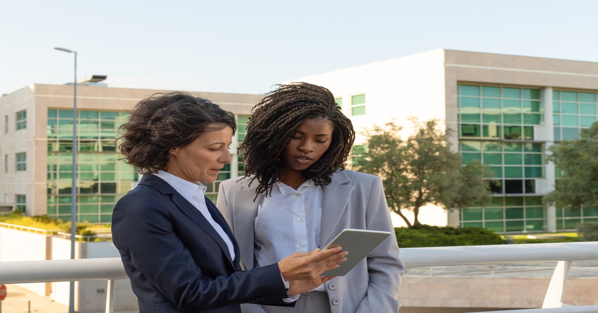 Duas mulheres com tablet nas mãos realizando a administração de um condomínio